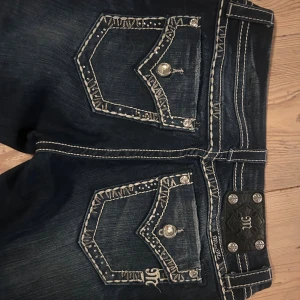 Miss Me jeans med broderade fickor - Mörkblå jeans från Miss Me med snygga broderade bakfickor, blingiga knappar och kontrastsömmar. Jeansen är bootcut och har en klassisk passform, med detaljer. Jag säljer dessa jeans då de är för stora för mig.  STORLEK: 28 x 33 tum. 
