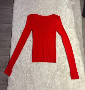 Röd ribbad långärmad topp - Säljer en snygg röd ribbad topp med lång ärm och rund halsringning. Toppen har en slim passform och är perfekt att styla med jeans eller kjol.