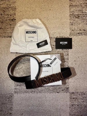 Moschino (Limited) - Brunt limiterat Moschino bälte med guldfärgat spänne och en unik design. Köpt på Miinto (juni 2024). Använd enstaka gång utan några tecken på användning.                                                -Nypris ≈ 2800kr (ej tillgängligt längre)                                                 -Skick: 10/10                                                         Hör av dig vid frågor och funderingar!