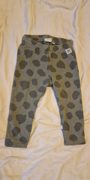 Gröna legging - Gröna leggings med mönster i mörkare gröna toner. Mjukt och stretchigt material med resår i midjan och möjlighet att dra åt för att de ska passa längre. De är något tvättpåverkade vilket syns på färgen. 