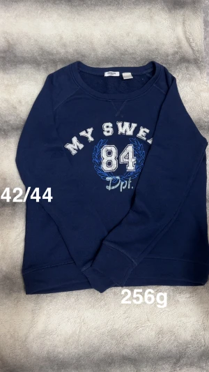 Mörkblå sweatshirt med tryck - Mörkblå sweatshirt från la redoute i vitt och blått framtill. Tröjan har rund halsringning och långa ärmar. Perfekt för en avslappnad och sportig stil. 🌸 Fint använt skick. Storlek 42/44