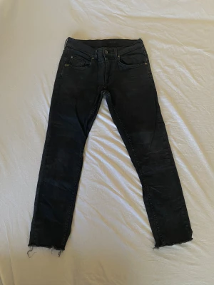 Tiger of sweden jeans - Svarta jeans från Tiger of Sweden med klassisk femficksdesign och rå, fransad kant vid benslut. Jeansen har en smal passform och är tillverkade i stretchig denim för extra komfort. Snyggt slitna detaljer och diskret logotyp vid fickan.