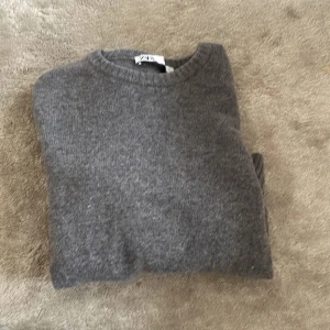 Grå stickad tröja från Zara - Mysig grå stickad tröja från Zara med rund halsringning och ribbade muddar. Perfekt för kyliga dagar och enkel att matcha med olika outfits.