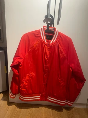 Röd bomberjacka  - Snygg röd bomberjacka från bikbok i S. Knappar längs framsidan o vita ränder på muddarna. Använd bara ett fåtal gånger☺️