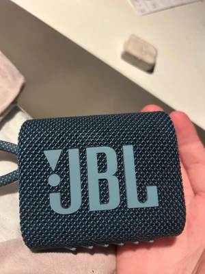 JBL Go 3 - Kompakt och portabel JBL Go 3 Bluetooth-högtalare i blått. Snygg design med slitstarkt tyg och integrerad rem. Perfekt för resor och utomhusbruk. Ser ut att vara i mycket gott skick utan synliga skador eller slitage pris kan diskuteras !!!.