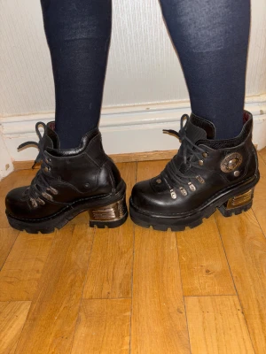 New Rock Planet kängor – svart läder – strl 37  - Svarta New Rock Planet-kängor i storlek 37, tillverkade i äkta läder med den klassiska metallklacken och robust platform-sula. Det här är en av New Rocks mest eftertraktade modeller, kända för sin hållbarhet och ikoniska alternativstil.  Skorna är i bra begagnat skick: lädret är fint, sulan stabil, och inga defekter som påverkar användning eller utseende. Metallklacken har normalt patinerat slitage (vanligt på äldre New Rock), men allt sitter stabilt och ser bra ut när de bärs. Inuti är de hela 