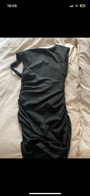 Svart oneshoulder långklänning SHEIN - Säljer en svart oneshoulder långklänning från SHEIN i stretchigt material. Klänningen har snygg rynkning längs sidan och är gjord i 90% polyester och 10% elastan. Perfekt för dig som vill ha en stilren och trendig look.