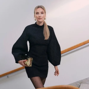 Svart kortklänning med ballongärmar - Supersnygg svart kort klänning från MQ med struktur och ballongärmar. Hög hals och figurnära passform som markerar midjan. Endast använd en gång!