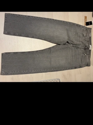 Grå jeans från Jack & Jones, straight fit Aldrig använda - Säljer ett par gråa jeans från Jack & Jones i modellen JJICHRIS som aldrig är använda. De har klassisk femficksdesign, rak passform och är tillverkade i slitstark denim. Perfekt för dig som gillar enkel och stilren look. Färg: grey denim.