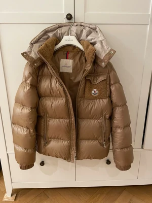 Moncler jacka - Beige guldig jacka från moncler, nk. Använd fåtal gånger. Storleken är 14,164. Köptes för 11,149. Den heter yule jacket, 236 - desert sand. Fraktas eller möts upp i sthlm! 🩷🩷 Små fläckar på sista sidan som man ser tydligt.