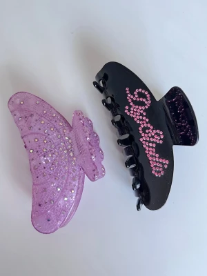 Hårklämmor med strass - Två hårklämmor, en svart med rosa strass och text samt en ljuslila med glittriga detaljer. Köper du innan kl 16:00 kan jag posta samma dag!