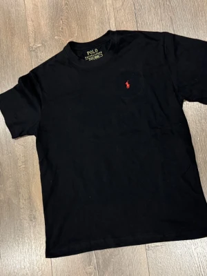 Svart t-shirt Polo Ralph Lauren  - Svart t-shirt från Polo Ralph Lauren, tillverkad i 100% bomull. Det står Storlek S men passar mig som har M.