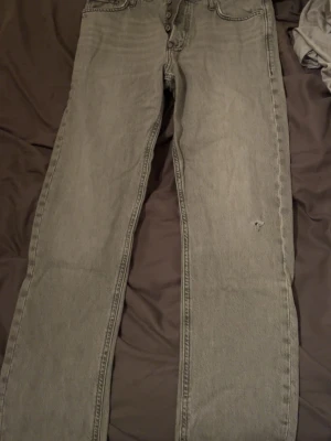 Grå loose fit jeans från Jack & Jones W31 L32 - Säljer ett par grå jeans från Jack & Jones, modell Loose/Chris. De har en loose passform och raka ben, med klassisk femficksdesign och knappgylf. Jeansen är tillverkade i bomull och har en cool, tvättad look.