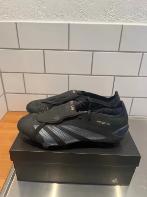 Adidas Predator elite fotbollsskor svart fg - Säljer ett par svarta Adidas Predator fotbollsskor då de är för små för mig, de är använda fåtal gånger då jag har använt ett par andra skor mer. De är i storlek 46 (eu) (28,4cm) och har fg dobbar. De har fåtal defekter men inget som påverkar prestandan på planen. Du får med allt som man får när man köper de nya, alltså påse,box och skorna. Tveka inte på att höra av dig vid minsta fundering.