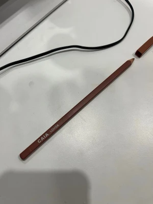 CAIA Lovisa läppenna ❣️ - Snygg läppenna från CAIA i färgen Lovisa. Pennan har en varm brun nyans och kommer i en klassisk träform med tillhörande lock. Perfekt för att definiera och forma läpparna med precision. Enkel att använda och passar till många olika looks.