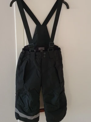 Varma täckbyxor 92 - Varma,fina täckbyxor i storlek 92 från hm. Justerbara hängslen,resor i midjan,snölås,dragsko nederkant på benen,mjuk flecce inne i byxorna baktill.