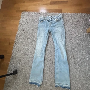 Ljusblå bootcut jeans  - Säljer ett par ljusblå jeans från Calvin Klein med klassisk bootcut passform. Jeansen har fem fickor, knapp och dragkedja fram samt slitna detaljer vid bensluten. 