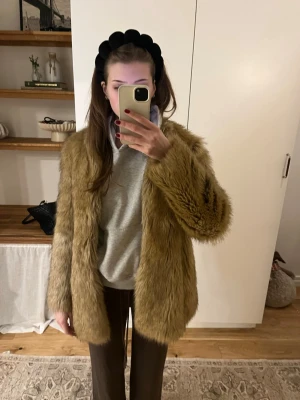 Beige pälsjacka med lång ärm - Säljer en snygg beige pälsjacka med lång ärm och rak passform. Jackan har en fluffig och mjuk känsla, perfekt för att hålla värmen under kyliga dagar. Enkel att styla till både jeans och dressade byxor.