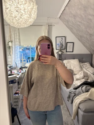 Beige stickad tröja med vida ärmar - Säljer en beige stickad tröja med rund hals och vida, trekvartsärmar. Tröjan har en loose passform och är supermjuk och skön, perfekt för lager på lager under höst och vinter. Passar till både jeans och kjol för en chill look.