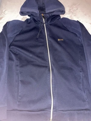 Hugo boss huvtröja  - En still ren guld/mörkblå Hugo boss hoodie. Knappt använd, Storlek XL. Pris kan diskuteras vid snabb och smidig affär.