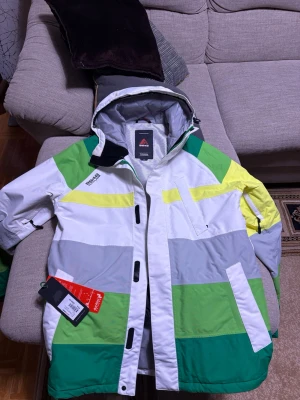 8848 Altitude vindjacka med färgblock - Snygg vindjacka från 8848 Altitude i storlek M. Jackan har coola färgblock i vitt, grått, grönt och gult, samt huva. Perfekt för äventyr i bergen. Ny pris ligger på 2200 kr.