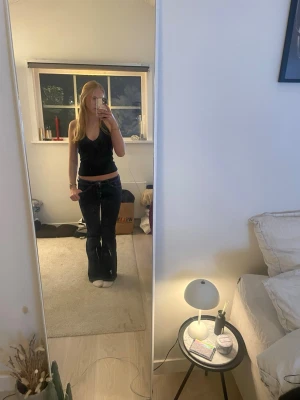 Svart glittrig linnetopp med v-ringning - Säljer en svart linnetopp med djup v-ringning och små glittriga detaljer upptill. Toppen är ärmlös och har en slim passform som sitter snyggt på kroppen. Helt ny. Hör av er för fler frågor💗