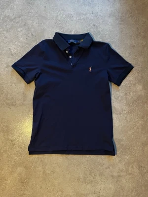 Mörkblå piké Polo Ralph Lauren - Säljer en klassisk mörkblå pikétröja från Polo Ralph Lauren. Inga defekter på tröjan säljer på grund av att jag har växt förbi den. Priset går att diskutera vid smidig affär.