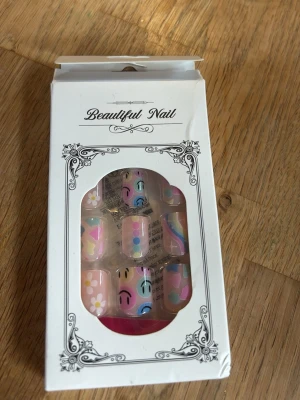 Färgglada lösnaglar med mönster - Säljer ett set lösnaglar från Beautiful Nail med olika färgglada motiv som smileys, blommor, hjärtan och regnbågarrrr. Perfekt för dig som vill ha roliga och kreativa naglar utan att måla själv. Tror från shein, men fina!!