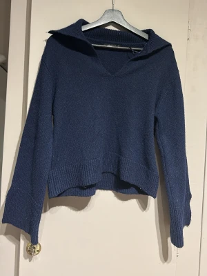 Stickad tröja från Ginatricot  - Blå stickad tröja från Ginatricot med v-ringning och slit i ärmsluten. 