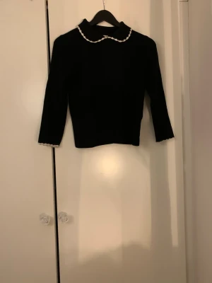 Svart stickad tröja med vit krage Reserved - Supersöt svart stickad tröja från Reserved med  trekvarts ärm och vita detaljer på kragen. Tröjan har även vita detaljer vid ärmsluten som ger en extra touch. Är en M men sitter tajt på mig som är S! 