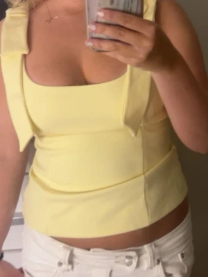 Gul croppad linnetopp med breda band - Snygg ljusgul croppad linnetopp med breda axelband och fyrkantig urringning. Toppen har en stilren och enkel design som passar perfekt till sommaren. Materialet känns mjukt och följsamt mot huden.