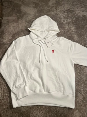 Ami Paris hoodie  - Säljer denna feta Ami Paris hoodie i vit. Strl M passa även S beroende på längd och vikt, tröjan är helt ny och oanvänd med taggar. Dm vid minsta fråga eller fundering🙌🏼