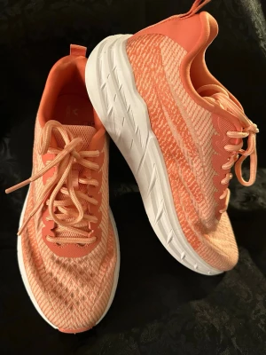 Korallfärgade sneakers med mönster sticker 39 - Snygga sneakers i korall och ljusorange med stickat mönster och vit, tjock sula. Skorna har rund tå, snörning och ventilerande meshmaterial. Perfekta för dig som gillar sportig stil och vill ha något som sticker ut med fräscha färger.