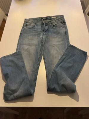 Replay ljusblå jeans med dragkedja - Säljer ett par ljusblå jeans från Replay med klassisk femficksdesign och dragkedja i gylfen. Jeansen har raka ben och snygga detaljer på bakfickorna. Perfekt för dig som gillar en avslappnad stil och vill ha ett par jeans med schysst tvätt. Längden är 30 tum.