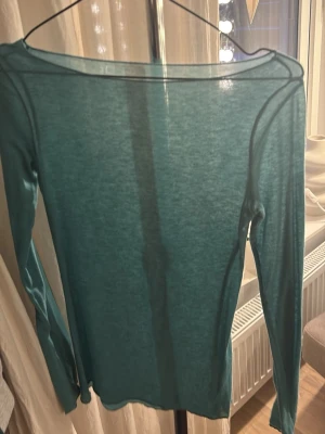 Turkos långärmad tunn topp - Säljer en turkos långärmad topp i tunt och lätt material. Toppen har en enkel och stilren design med rund hals och smal passform. Perfekt att styla med jeans eller kjol för en fräsch look.
