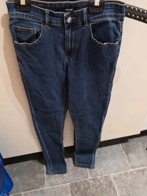 Mörkblå skinny jeans från Bik Bok - Säljer ett par mörkblå skinny jeans från Bik Bok i klassisk femficksmodell. Jeansen har kontrastsömmar, normalhög midja och smal passform hela vägen ner. Tillverkade i stretchig denim för extra komfort.