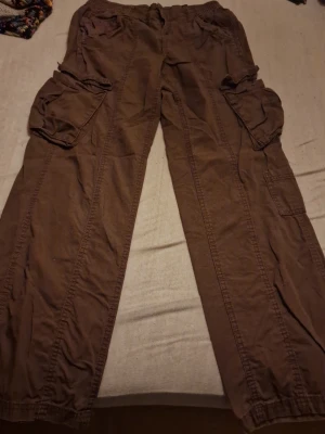 Bruna cargopants från H&M Divided - Bruna cargopants från H&M Divided i storlek 34. Byxorna har flera stora fickor på sidorna och resår i midjan. Tillverkade i bomull och har en loose passform som ger en avslappnad vibe. Använda, inga synliga deffekter. Priset som står gäller, kan möjligtvis diskuteras 🫶