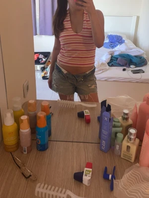 Randig halterneck linnetopp - Säljer en snygg randig halterneck linnetopp i rosa, rött och vitt. Toppen har djup v-ringning och är ärmlös med smala axelband som knyts i nacken. Perfekt för varma sommardagar och ger en fräsch och ungdomlig look.