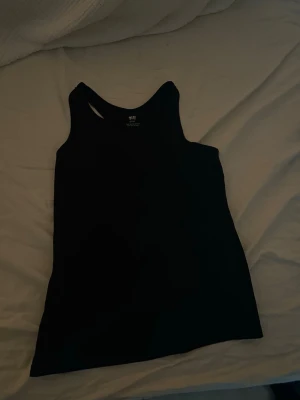 Svart linnetopp från H&M - Säljer en enkel och stilren svart linnetopp från H&M. Toppen är ärmlös med klassisk rund halsringning och rak passform. Perfekt att matcha med jeans eller kjol för en clean look. Materialet är mjukt och bekvämt bomull.