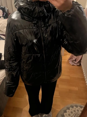 Svart pufferjacka  - Säljer en svart, glansig pufferjacka från Nelly. Den är i storlek m men passar även om man har S i vanliga fall som jag. 