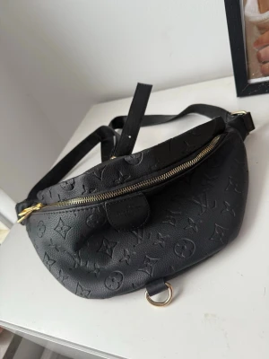 Svart supersnygg mönstrad axelväska  - Säljer en svart axelväska från med klassiskt svart mönster utanpå & svart grått inuti, aldrig använts. Väskan har guldfärgade detaljer och dragkedjor, justerbar rem och innerfoder med märkesloggor. Perfekt för dig som vill ha en snygg och praktisk väska med lyxig känsla. 