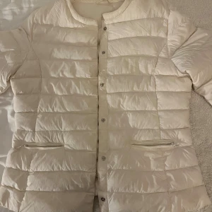 Vit dunjacka - Snygg vit dunjacka med knappar. Tunnt material och lätt att matcha med olika outfits. Okänt märke och storlek men passar mig som vanligtvis har S