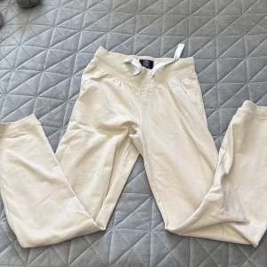 Beige mjukisbyxor Vinson Polo Club XS - Snygga beige mjukisbyxor från Vinson Polo Club i storlek XS. Byxorna har ribbad midja med snörning och muddar vid bensluten. Mjukt bomullsmaterial och diskret logga på höften. Perfekta för chill eller träning.