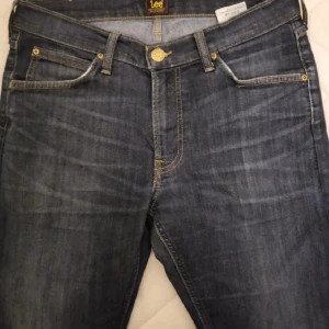 Mörkblå Lee jeans W31 L32 - Snygga mörkblå jeans från Lee med klassisk femficksdesign och raka ben.  Mycket bra skick knappt använd dom