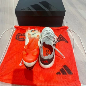 Adidas Copa Pure  - Säljer ett par Adidas Copa Pure fotbollsskor i vitt, grått och svart med röda detaljer. Skorna har snörning och är designade för optimal bollkontroll. Sulan har dobbar för spel på gräs. Kommer med originalpåse. Perfekta för dig som vill dominera på planen. St 42. Ej använda av mig, fick dom av stadium. Pris kan diskuteras 