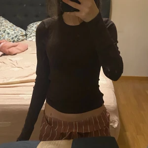 Brun långärmad tröja  - Säljer en brun långärmad tröja från New Yorker i storlek XS. Tröjan är ribbad och har en rund halsringning. Den är slim fit och sitter snyggt på kroppen, perfekt att styla med jeans eller kjol. Materialet är mjukt och stretchigt, vilket gör den skön att ha på sig.
