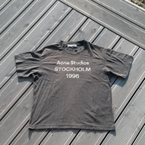 Svart Acne Studios t-shirt XS - Svart t-shirt från Acne Studios med vit text 'Acne Studios STOCKHOLM 1996' på bröstet. Otroligt snygg och matchar till allt. Storlek Xs motsvarar S skulle jag påstå i vanliga storlekar. Självfallet äkta! Köpt ny för 3199 kr och det är otroligt bra skick på den.