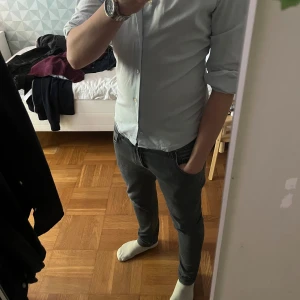 Ljusblå skjorta från Pasqui - Snygg ljusblå skjorta från Pasqui, tillverkad i Italien. Skjortan har vit krage och vita manschetter, samt diskreta ränder på insidan av kragen. Klassisk passform med knappar framtill och lång ärm. Perfekt för dig som gillar stilrena och fräscha plagg. Skriv vid fundering!🍾