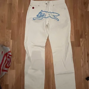 Icecream bbc jeans - Unika vita jeans från Icecream med blå grafiska tryck på både fram- och baksida, inklusive en tecknad hund och siffror. Klassisk femficksmodell med raka ben och normal passform. 