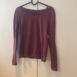 Vinröd långärmad tröja från 157 - En enkel och snygg vinröd långärmad tröja från 157, gjord i mjuk bomull med lite stretch för skön passform. Tröjan har en rundad hals och är perfekt att matcha med jeans eller kjol. Materialet är 95% bomull och 5% elastan.